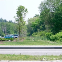 040609NatickMallROW PART 8 - Natick Mall.
In 2006 and 2007, Natick Mall is expanding to become the largest mall in New England. Looking across Speen Street from the new section (the old Wonderbread Plant), we see the old Wonderbread Spur Line heading downhill and east to meet the main CRT at Lake Cochituate.