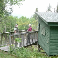 070601ColdRiverCamp_BernieAndJillAtACabin We arrived ahead of the crowd, so we looked over a few of the cabins. Many of them, like this one, perch over a ravine.