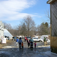 070303NatickCommunityOrganicFarm1 A view back from the main barn along THIS year's entrance road, past the offices and greenhouse toward Memorial School. Over the white car, you can see the farm's sugar shack. (Zoom in, to see its cords of firewood.)