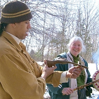 070303WampanoagSpoonEtAl3 The Wampanoag exhibitor, <a href=http://www.mcnaa.org/Speakers/annawon_weeden.html>Annawon Weeden</a>, brought these artifacts from Cape Cod. Here he holds up that duck spoon, as Jill holds a flute and drum. (No, she's not using the flute to beat the drum.)
