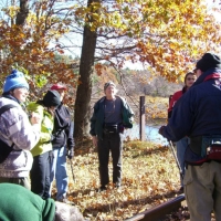 061026RockyNarrows3 At the railroad bridge across the Charles River, Bernie at right, back to us) explains.